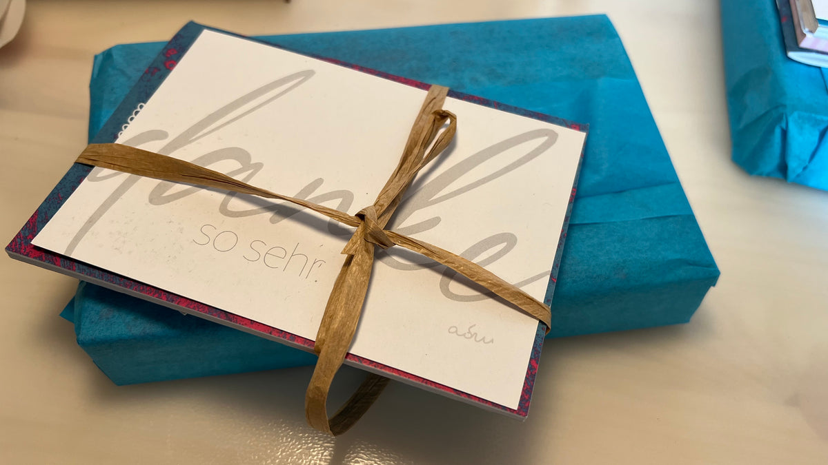 In Geschenkpapier eingeschlagene Bücher mit rot-weißer Kordel als Geschenkverpackung.